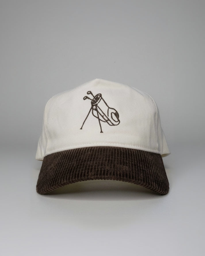 White cap with brown brim and black logo on a white surface with a blurred background